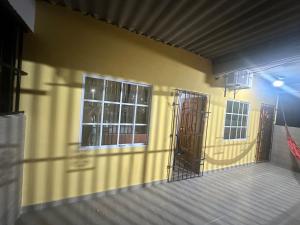 un bâtiment jaune avec deux portes et fenêtres dans l'établissement Hostal el viajero, à Soledad
