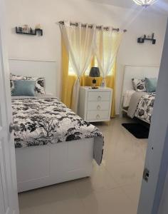a white bedroom with two beds and a night stand at Y Beautiful and comfortable in Moca