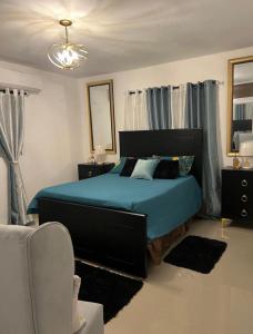 een slaapkamer met een bed met blauwe lakens en een spiegel bij Y Beautiful and comfortable in Moca