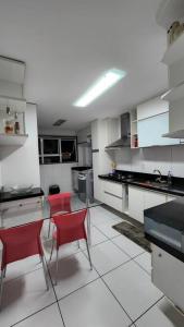卡波布里奧的住宿－Apartamento Cobertura em Cabo Frio 3 suítes，厨房配有红色的椅子和桌子