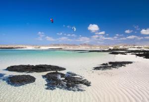 a person is flying a kite over a beach at Villa Colibri Azul in Lajares