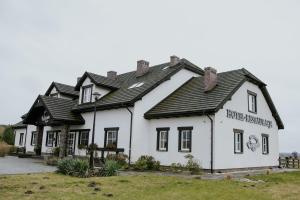 a white house with a black roof at Hotel Weranda Łopuszno in Łopuszno