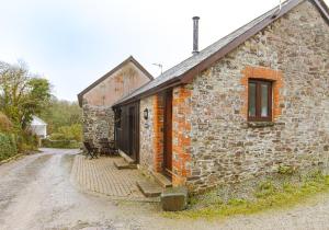 an old stone building with a window on a dirt road at Linhay, Pattard in Hartland