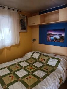 Una cama con edredón en un dormitorio en Les Grands Pins emplacement numéro 103, en Le Castellet