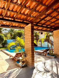 une terrasse avec une pergola en bois et une piscine dans l'établissement Trilha dos Ventos Cumbuco, à Cumbuco