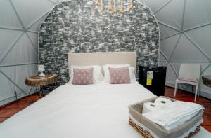 a large bed in a room with a brick wall at Ovalulú Glamping Hotel in Santa Cruz de Barahona