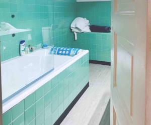 La salle de bains est pourvue de carrelage vert, d'une baignoire et d'un lavabo. dans l'établissement Self-Check in Sunny & Charming Apt, à Coimbra