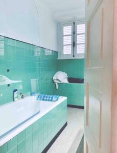 un bagno piastrellato verde con vasca e lavandino di Self-Check in Sunny & Charming Apt a Coimbra