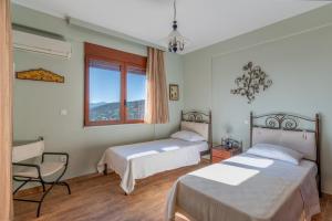 a bedroom with two beds and a chair and a window at Villa Lumière- Avantes in Agioi Apostoli