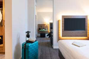 a hotel room with a suitcase and a flat screen tv at Moxy Aberdeen Airport in Dyce