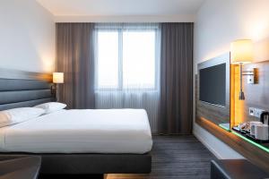 a hotel room with a bed and a television at Moxy Aberdeen Airport in Dyce