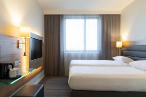 a hotel room with two beds and a television at Moxy Aberdeen Airport in Dyce