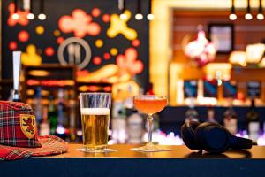 two glasses of beer sitting on a bar at Moxy Aberdeen Airport in Dyce