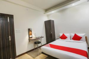 1 dormitorio con cama con almohadas rojas y escritorio en OXY Royal Residency en Ranchi