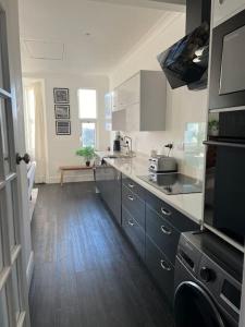 a kitchen with white cabinets and a wooden floor at Hill Grove 2 Bedroom Apartment in Southend-on-Sea