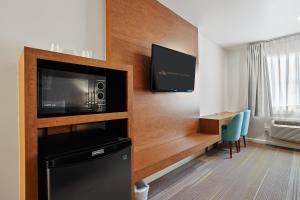 a hotel room with a microwave and a tv and a desk at Brookhurst Plaza Inn in Anaheim