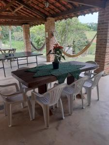 una mesa con sillas blancas y una mesa con una planta. en Casa Cabocla da Mantiqueira, en Bueno Brandão