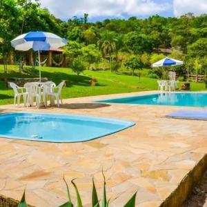a swimming pool with a table and chairs and an umbrella at Casa Cabocla da Mantiqueira in Bueno Brandão