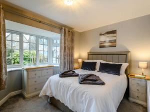 een slaapkamer met een bed met witte lakens en ramen bij 3 Bed in Corfe Castle 81369 in Corfe Castle