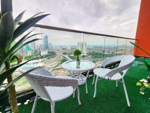 three chairs and a table on a balcony with a view at Loft Suite CityView near JB CIQ 7Pax in Johor Bahru