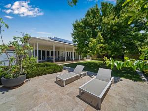 a patio with two white chairs and a building at Stay at beautiful Rea in Shepparton