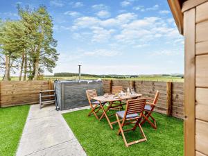 een patio met een tafel en stoelen op het gras bij 1 Bed in Biggar 91248 in Libberton