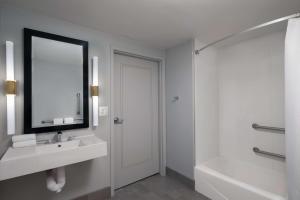 a bathroom with a sink and a mirror and a tub at The Starling Atlanta Midtown, Curio Collection by Hilton in Atlanta +117 photos