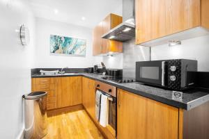 una cucina con armadi in legno e forno a microonde di Funky Arcadian Center Apartment By Azura Nights a Birmingham