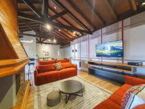 uma sala de estar com mobiliário laranja e uma televisão de ecrã plano em Duplex Cobertura - Gramado Wish Serrano em Gramado