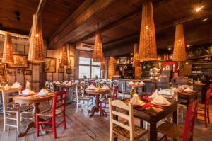 um restaurante com mesas, cadeiras e lustres em Duplex Cobertura - Gramado Wish Serrano em Gramado