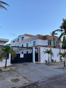 un edificio blanco con una puerta negra y palmeras en Lindo Flat pé na areia en Salvador
