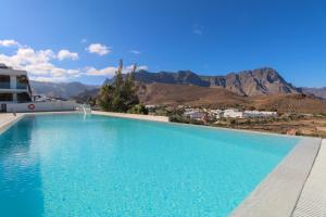une grande piscine avec des montagnes en arrière-plan dans l'établissement Agaete 2BR Coastal Retreat, à Agaete