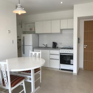 uma cozinha com uma mesa branca e um frigorífico branco em Departamento amoblado 1 dormitorio Familiar em Bahía Blanca