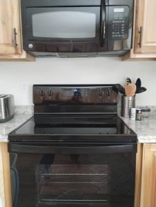 a microwave above a black stove in a kitchen at Beargrass Lodging & RV Resort in Hungry Horse