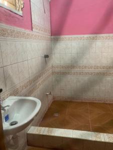 a bathroom with a white sink and pink walls at Ocean Breeze Hotel & Restaurant in Achien