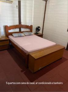 a bed with a wooden frame in a room at Casa de Praia - Prainha in Aquiraz