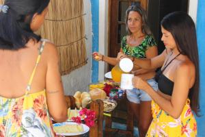 three women standing around a table with food at Casulo Hostel in Porto De Galinhas