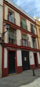 ein rot-weißes Gebäude mit Balkonen darauf in der Unterkunft Apartamentos Marco Sancho Centro-Alameda-Setas in Sevilla