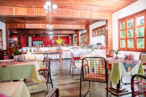 uma sala de jantar com mesas e cadeiras brancas em Recanto das Hortencias Hotel em Monte Verde