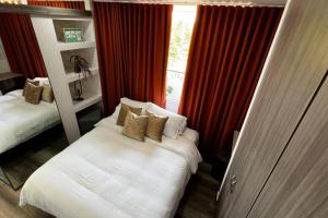 1 dormitorio con 2 camas y una ventana con cortinas rojas en Noah apartasuite 602, en Cali