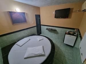 a bathroom with a toilet and a tv on the wall at Eclipse Motel in Recife