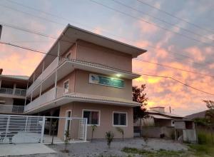 een roze gebouw met een zonsondergang op de achtergrond bij Pousada Provinelli in Palhoça