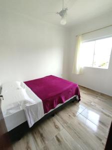 een slaapkamer met een bed met een paarse deken bij Pousada Provinelli in Palhoça