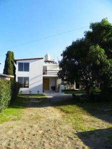 a white house with a tree in front of it at Casa Fresnos in Amealco