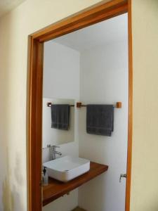 La salle de bains est pourvue d'un miroir, d'un lavabo blanc et de serviettes noires. dans l'établissement Casa Fresnos, à Amealco