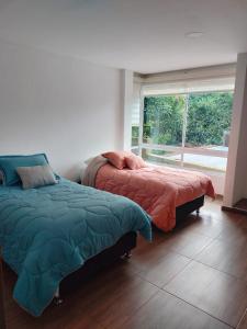 two beds in a room with a window at JOMAWA Vivienda Turística in Guayabal