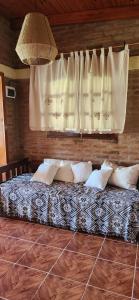 1 dormitorio con cama con almohadas y ventana en Casa de Campo Los Sauces in 