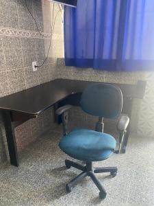a black desk with a blue chair and a table at Casa Geminada in Contagem