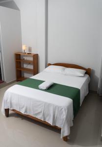1 dormitorio con 1 cama con manta verde y blanca en Hospedaje Humazapa Tarapoto, San Martín, en Tarapoto
