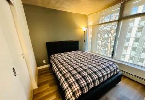 sypialnia z łóżkiem w pokoju z 2 oknami w obiekcie Downtown Luxe w mieście Vancouver